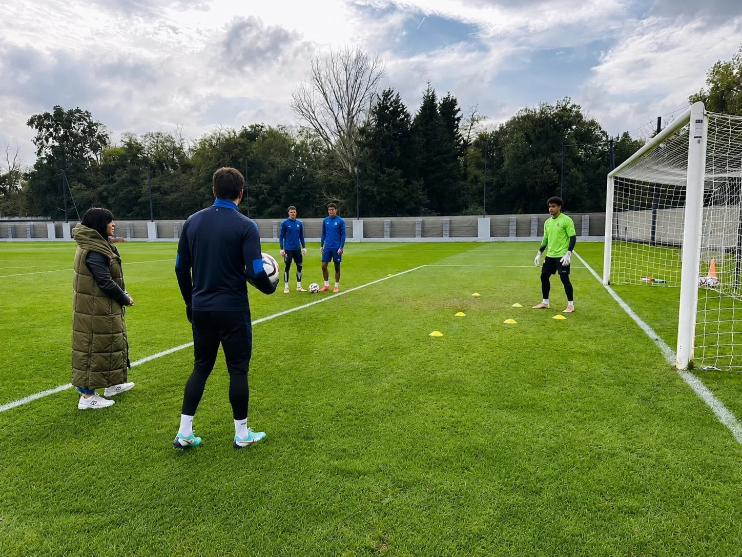 Séance de terrain avec staff et joueurs sur un terrain de football.